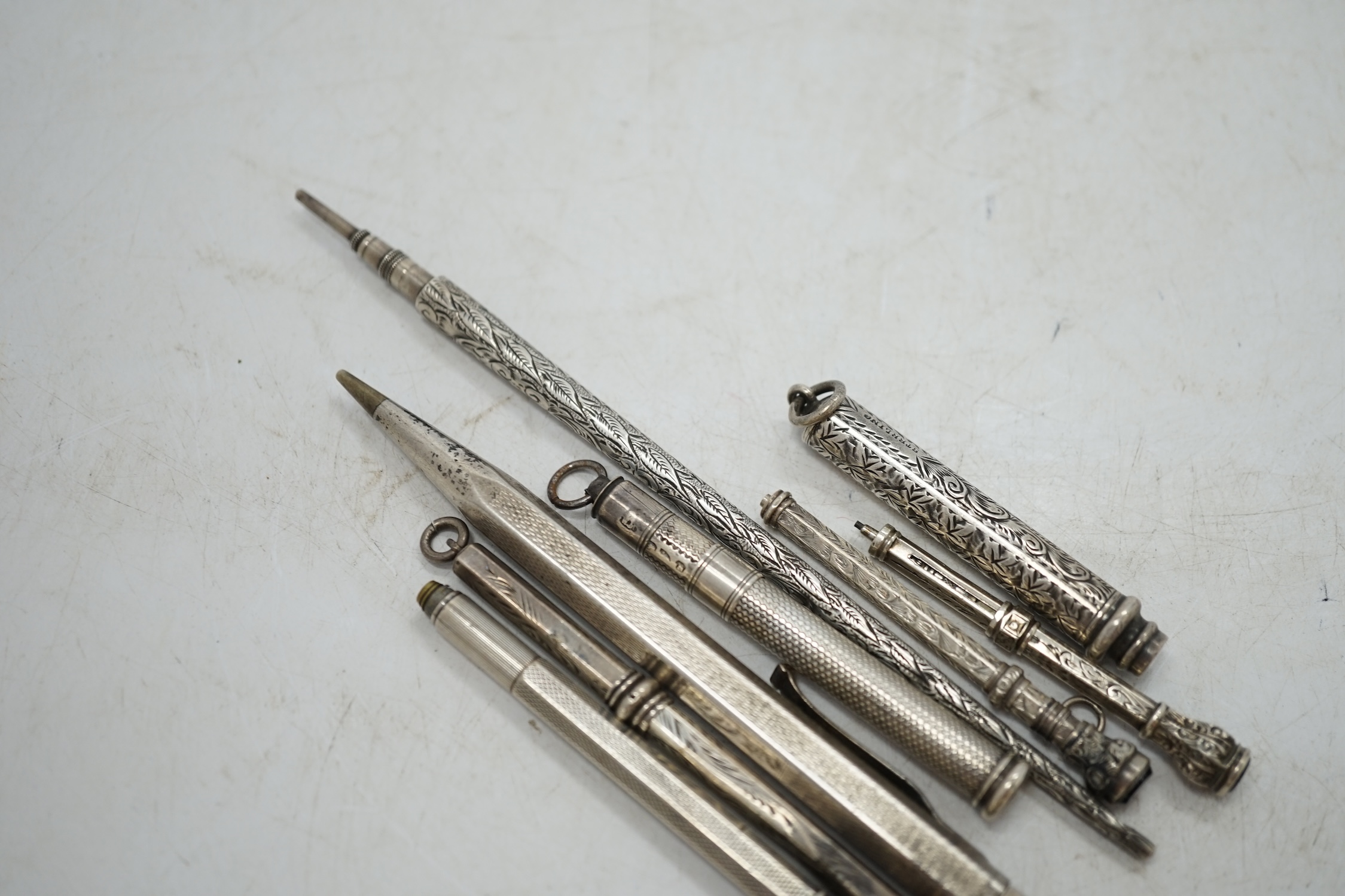 An engine turned silver cased Yard-O-Led pencil, three silver cased propelling pencils, a sterling cased propelling pencil and three white metal cased pencils. Condition - fair